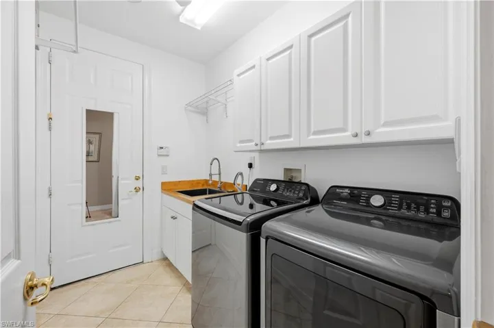Laundry room featuring cabinet space, light tile patterned flooring, and separate washer and dryer