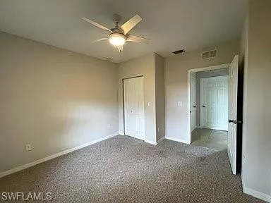 Unfurnished bedroom featuring visible vents, ceiling fan, baseboards, carpet flooring, and a closet