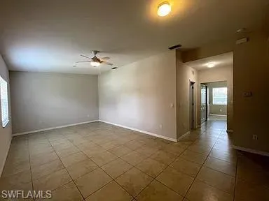 Tiled spare room with visible vents, plenty of natural light, baseboards, and ceiling fan