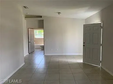Tiled spare room featuring visible vents and baseboards