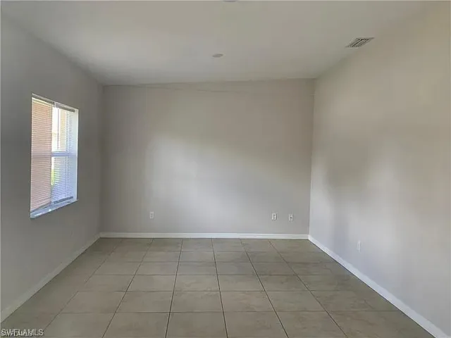 Spare room with light tile patterned flooring, visible vents, and baseboards