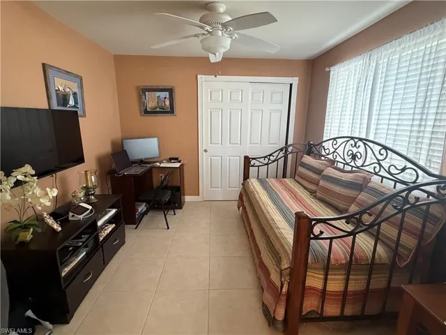 Bedroom featuring light tile patterned floors, a closet, ceiling fan, and an office area