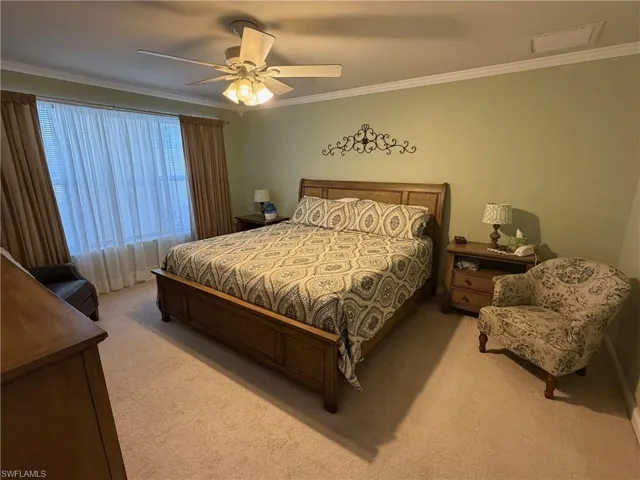 Carpeted bedroom with crown molding and a ceiling fan