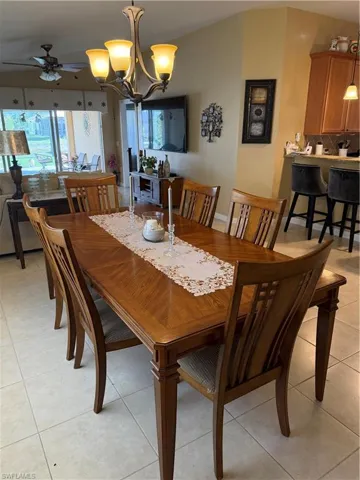 Dining room with a chandelier, light tile patterned floors, and a ceiling fan