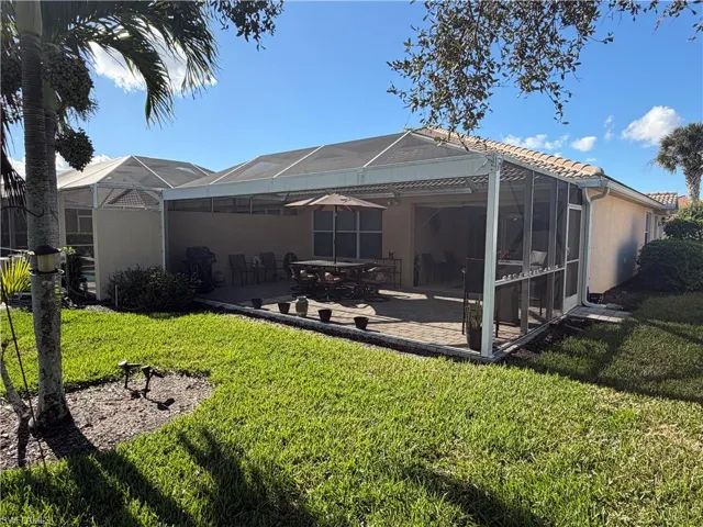 Rear view of property with a lanai, a sunroom, a lawn, and a patio area