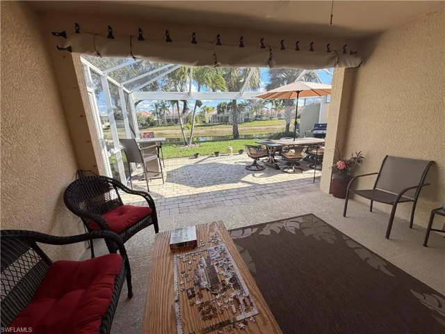 View of patio with a sunroom, a lanai, outdoor dining area, a ceiling fan, and a water view