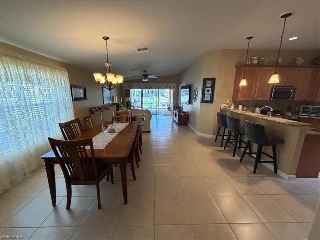 Dining space with ceiling fan, light tile patterned flooring, a chandelier, recessed lighting, and vaulted ceiling