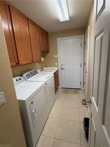 Laundry room featuring cabinet space, light tile patterned floors, and separate washer and dryer