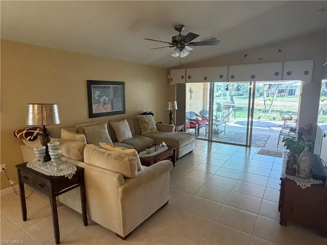 Living room featuring lofted ceiling, light tile patterned floors, and a ceiling fan