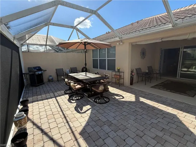 View of patio featuring outdoor dining space, area for grilling, glass enclosure, and a sunroom
