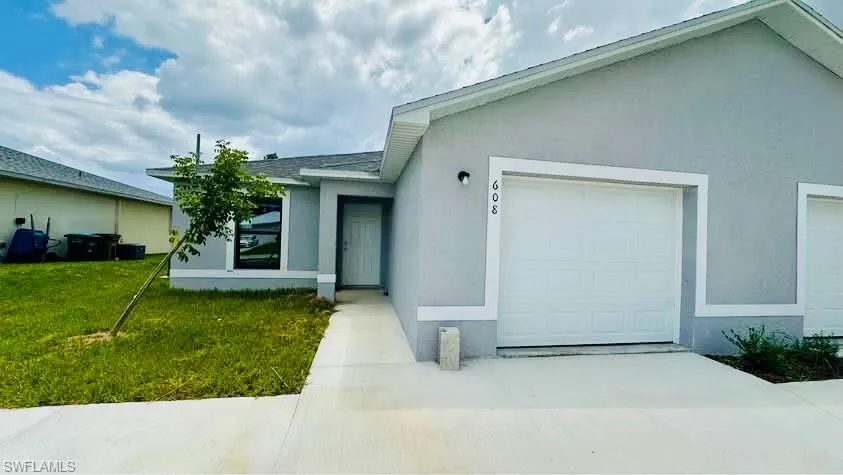 Single story home with stucco siding, an attached garage, a front lawn, and driveway