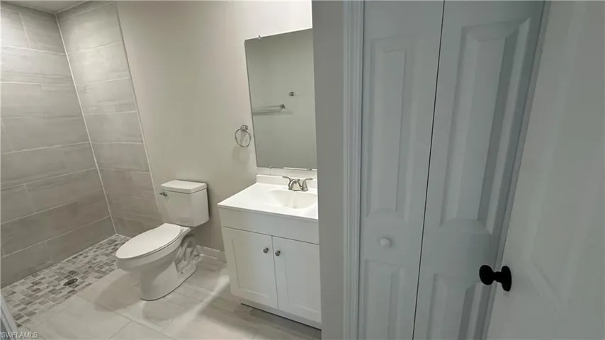 Bathroom featuring vanity, a shower stall, a closet, and light tile patterned flooring