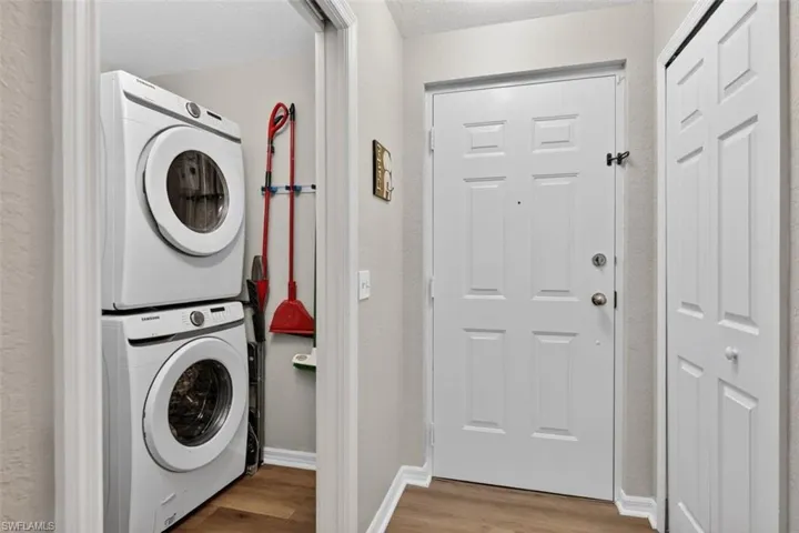 Laundry room featuring light wood-style flooring and stacked washer / dryer