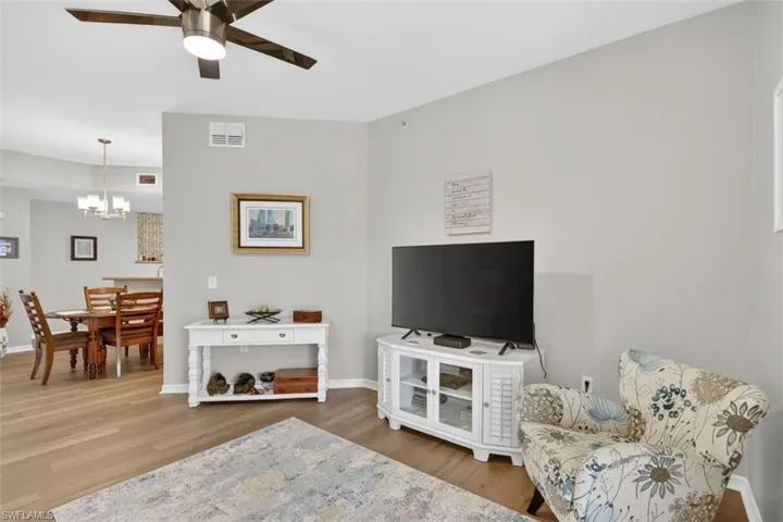 Living area featuring light wood-type flooring, a ceiling fan, and hanging lights