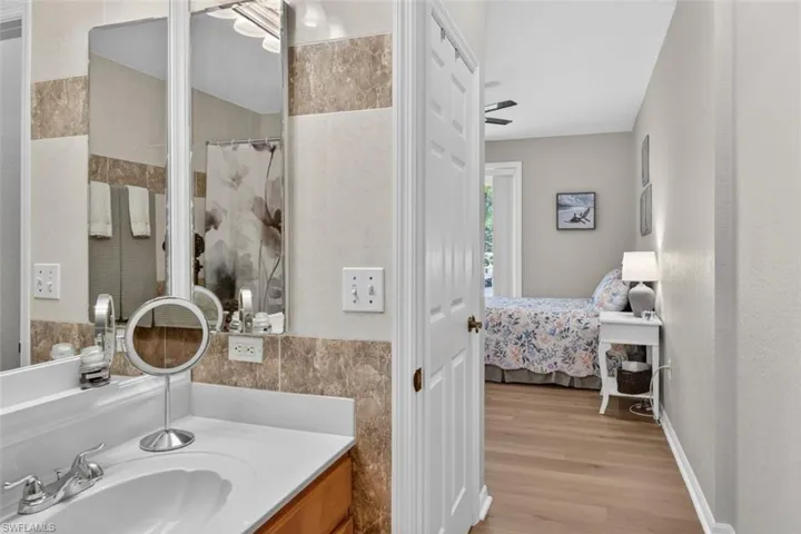 Ensuite bathroom with vanity, tile walls, light wood-type flooring, and a shower with shower curtain