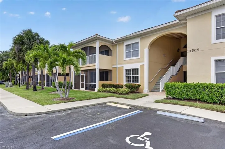 View of property featuring stairway and uncovered parking