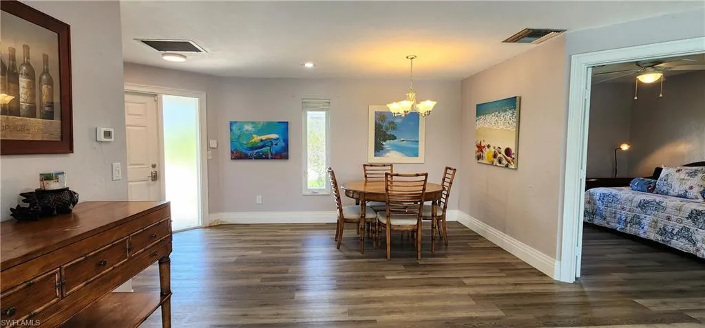 Dining space with dark wood-type flooring and ceiling fan with notable chandelier