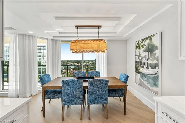 Dining area has custom lighting and draperies, as well as beautiful ceiling detail and floor to ceiling windows