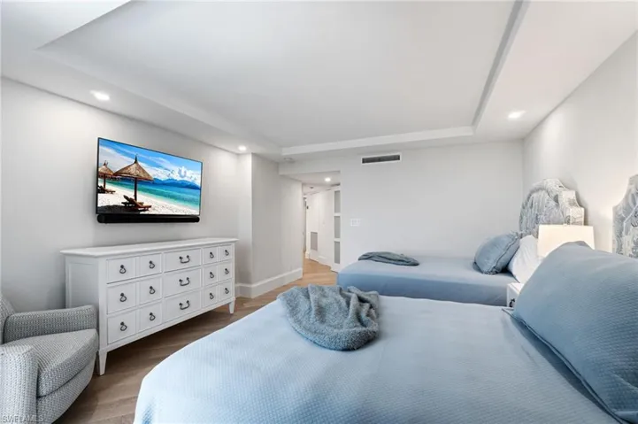 Guest Bedroom  with wood floors, a tray ceiling, and recessed lighting has an en-suite bathroom.