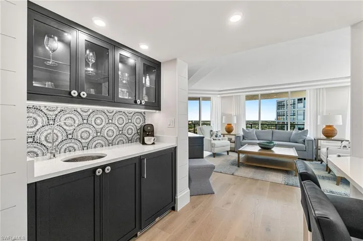 Bar area, perfect for cocktails or coffee station, with navy blue cabinetry, quartz counters, custom sink, glass insert cabinets, and an integrated wine/beverage refrigerator