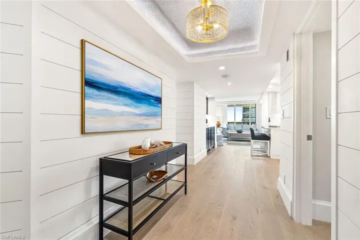 Foyer with custom light fixture and tray ceiling with custom wall treatment. (Art is virtually staged)