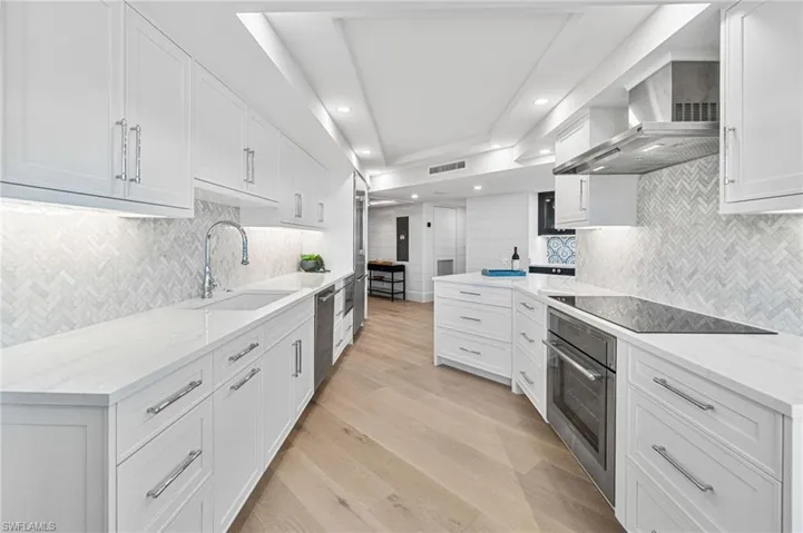 Kitchen featuring herringbone backsplash, white cabinets, quartz counters, Thermador induction cooktop and a built-in drawer microwave