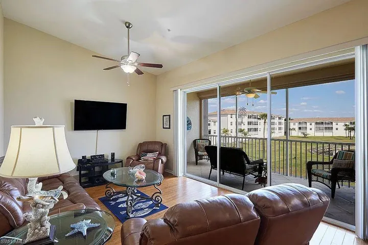 Living room with a ceiling fan, wood finished floors, and vaulted ceiling