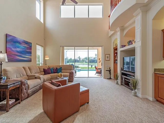 Living room featuring built in shelves, a towering ceiling, and light carpet