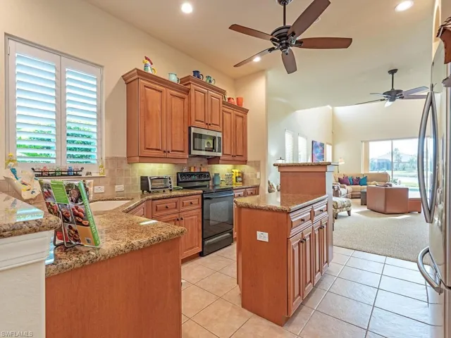 Kitchen with decorative backsplash, ceiling fan, light tile patterned floors, a kitchen island, and stainless steel appliances