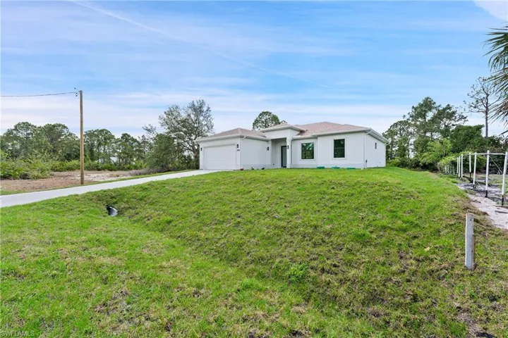View of front of property featuring driveway, a garage, a front lawn, and stucco siding