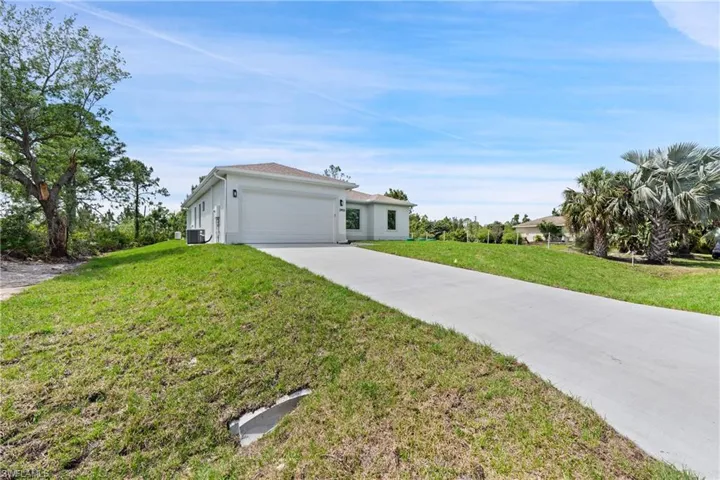 View of front facade featuring driveway, a front lawn, a garage, and stucco siding