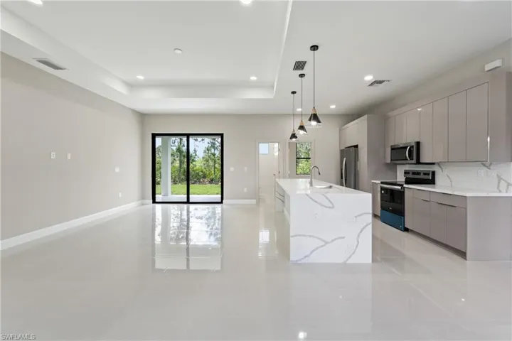 Kitchen featuring modern cabinets, gray cabinets, appliances with stainless steel finishes, decorative light fixtures, and recessed lighting