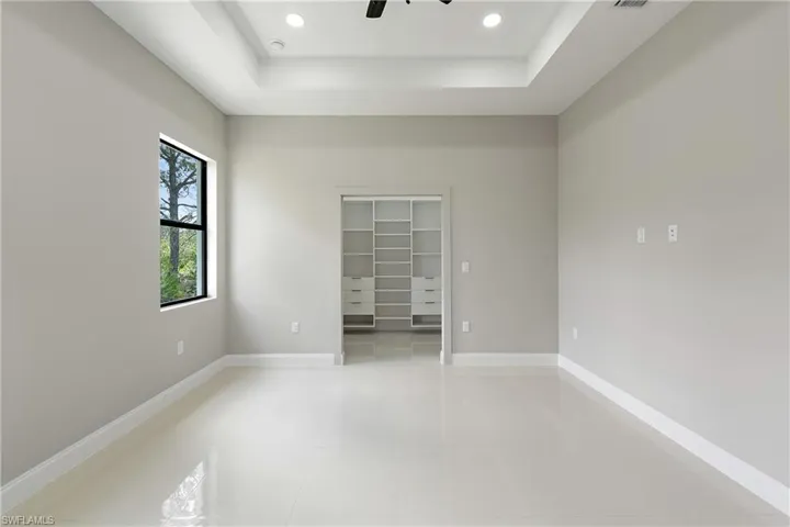Unfurnished room featuring a raised ceiling, recessed lighting, and light tile patterned flooring