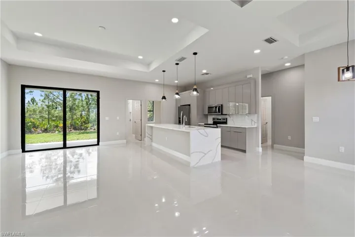 Kitchen with a center island with sink, gray cabinetry, decorative light fixtures, appliances with stainless steel finishes, and modern cabinets