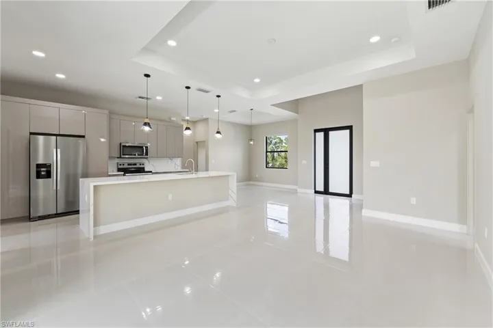 Kitchen with a large island, stainless steel appliances, pendant lighting, a tray ceiling, and light tile patterned floors