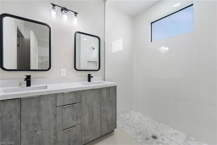 Bathroom with tiled shower and double vanity
