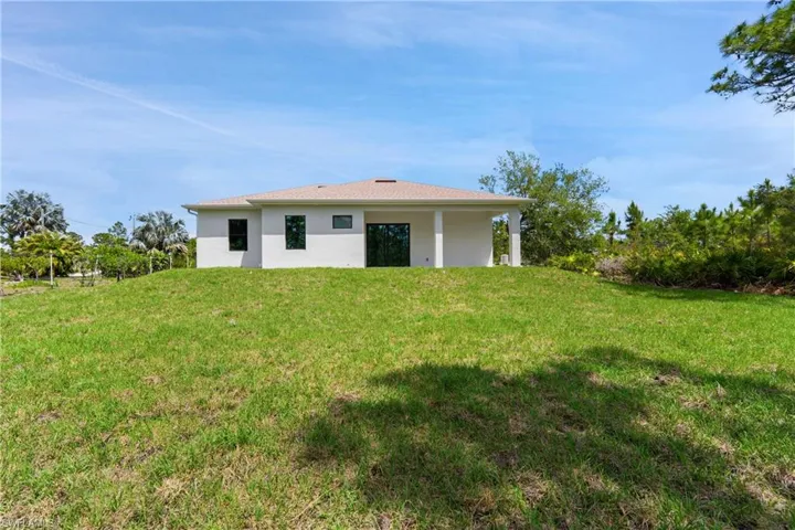Back of house featuring stucco siding, a yard, and a patio area