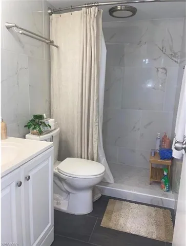 Bathroom with a stall shower, vanity, and dark tile patterned flooring