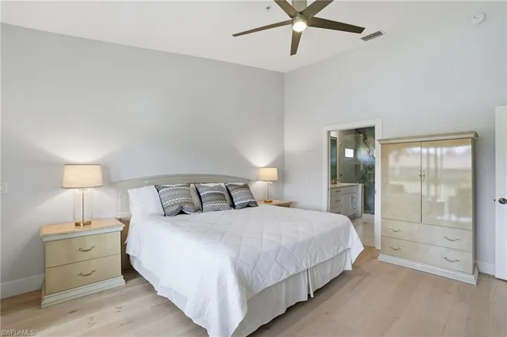 Bedroom with light wood finished floors, ensuite bath, and ceiling fan