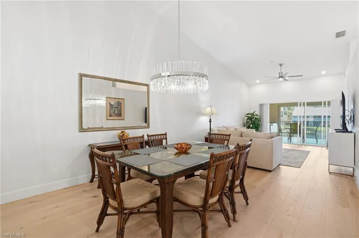 Dining room with light wood-type flooring, vaulted ceiling, a ceiling fan, and a chandelier