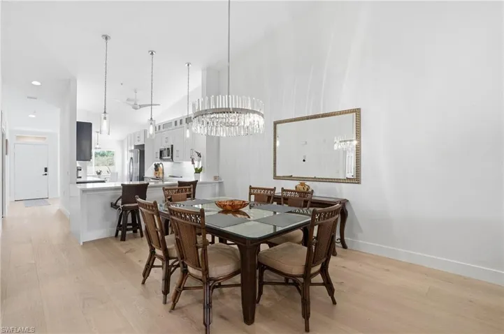 Dining space with light wood-type flooring, a chandelier, and a high ceiling