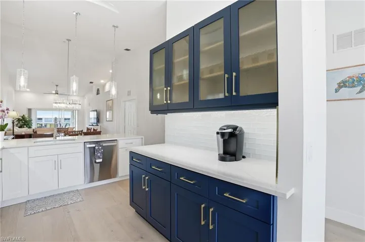 Kitchen featuring stainless steel dishwasher, pendant lighting, light stone countertops, light wood finished floors, and open floor plan