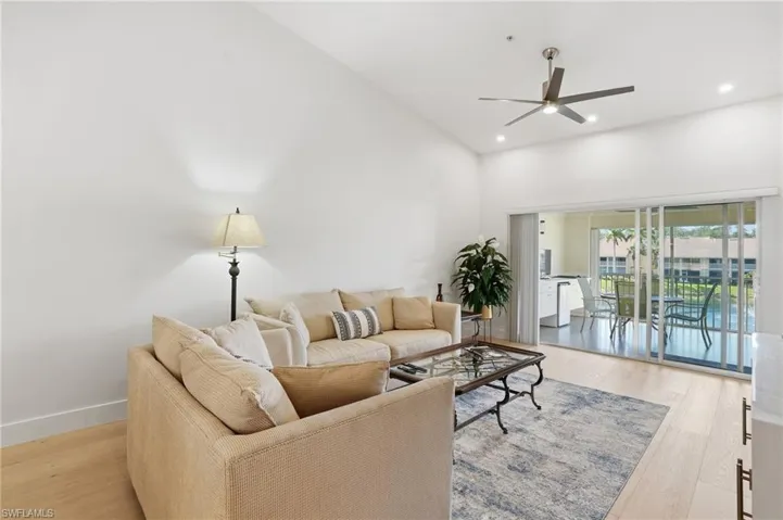 Living area with ceiling fan, light wood finished floors, recessed lighting, and vaulted ceiling