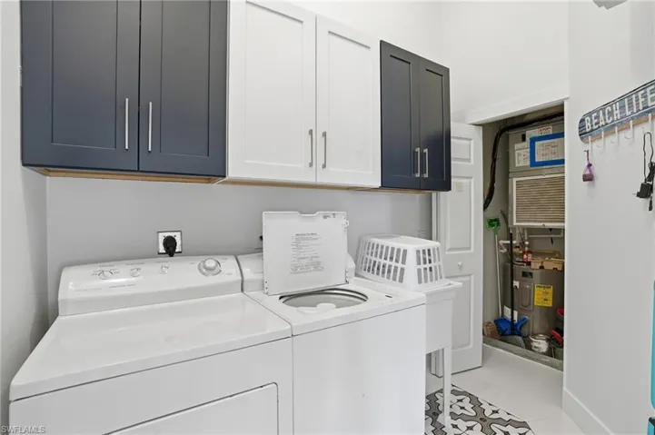 Laundry room featuring cabinet space, separate washer and dryer, heating unit, and light tile patterned flooring