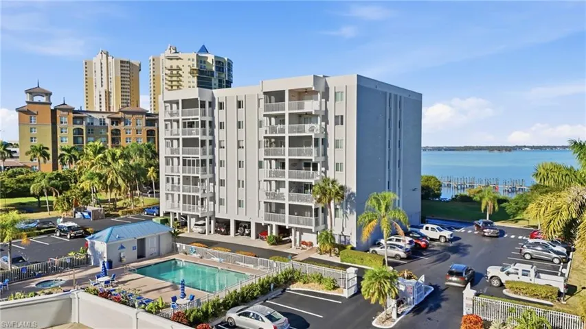 View of apartment building / complex featuring a water view and uncovered parking