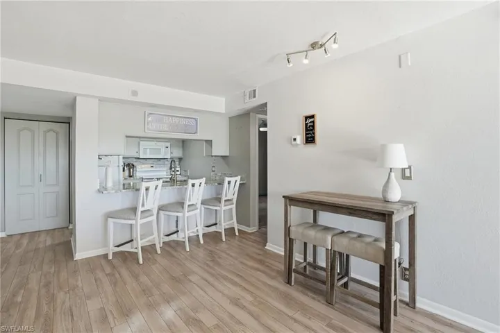 Kitchen featuring a kitchen breakfast bar, light countertops, white appliances, light wood finished floors, and a peninsula