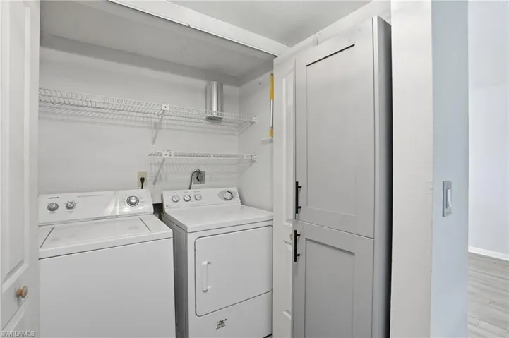 Laundry area with washing machine and clothes dryer and wood finished floors