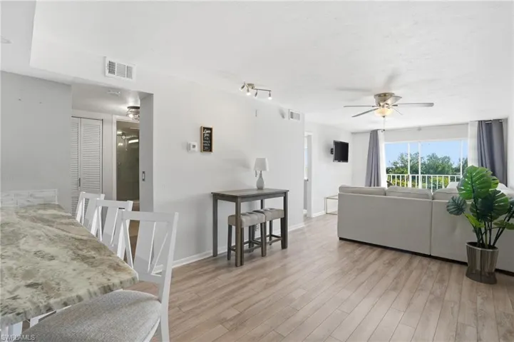 Living area featuring ceiling fan, light wood-type flooring, and a textured ceiling