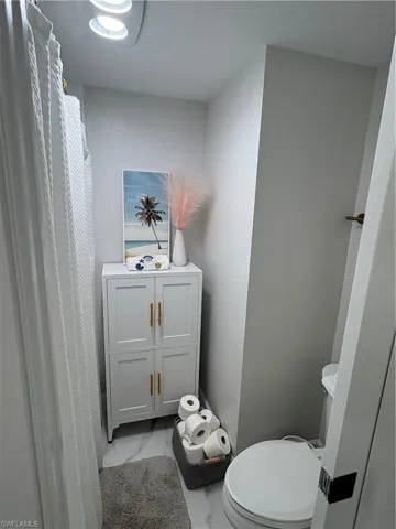 White built-in floor-to-ceiling cabinetry featuring gold-tone hardware and light-toned stone-finish flooring