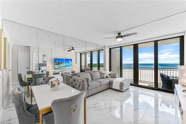 Floor-to-ceiling mirror wall, large-format polished tile flooring, sliding glass door panels, ceiling fan, and balcony access